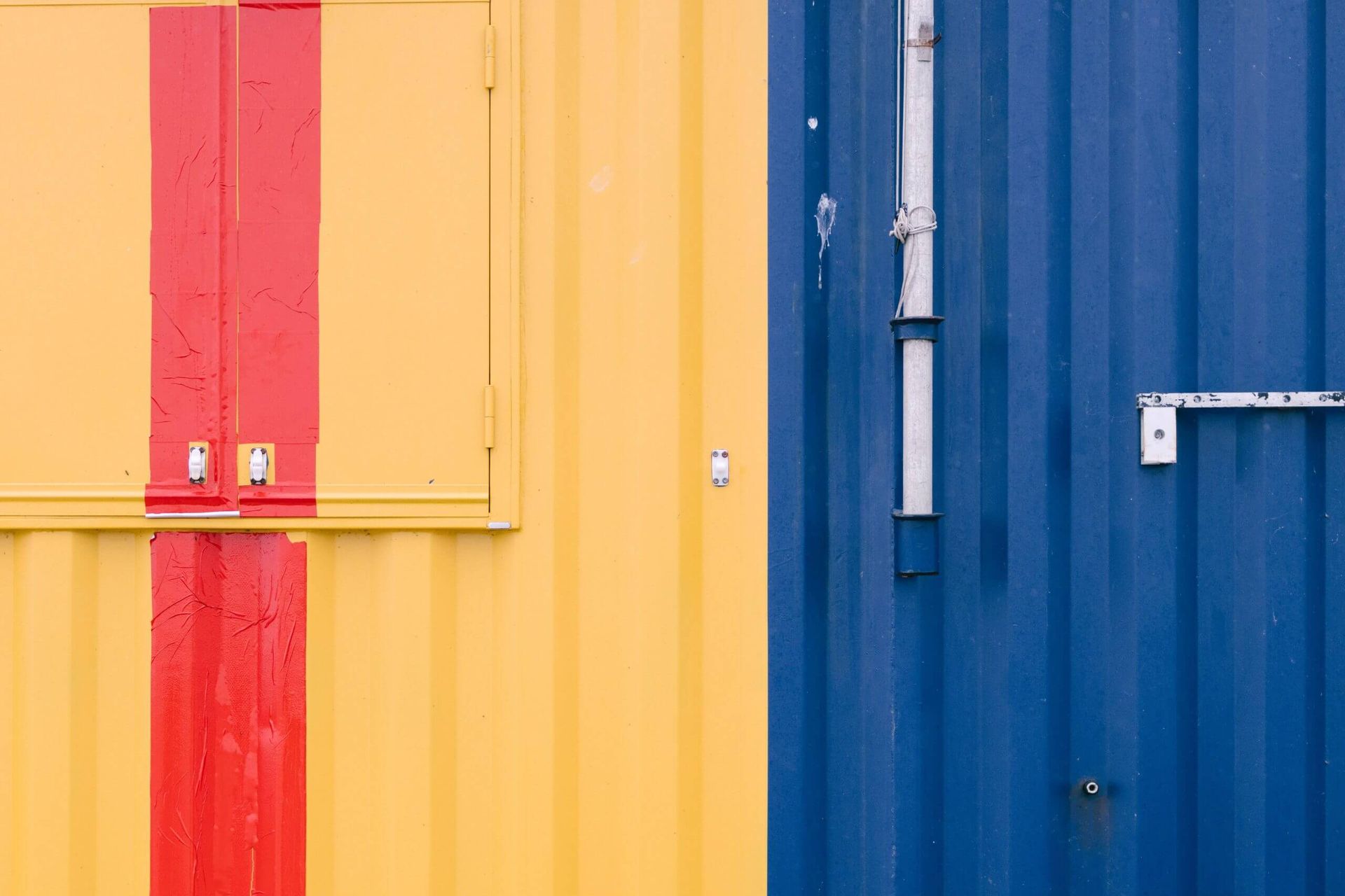 A yellow and blue shipping container with a red stripe on the side.