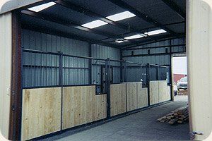 A horse stable with wooden walls and a metal roof.