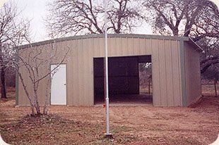 A large metal building with a white door and a flag pole in front of it.