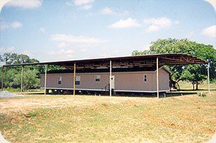 A mobile home with a canopy over it in a field.