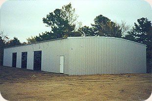 A large white building with a lot of doors and trees in the background