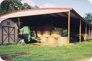 A barn filled with hay bales and a combine harvester.