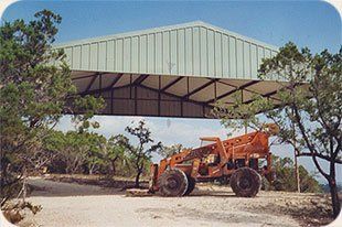 An orange tractor is parked under a green roof