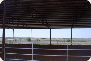 A covered area with a white railing and a view of a field.