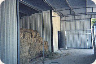 A shed filled with hay bales and a door.