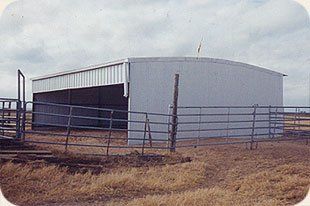 A large white building with a fence around it in a field.