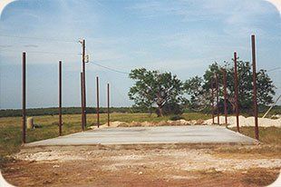 A concrete base is being built in a field with trees in the background.