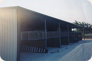 A large metal building with a covered porch and a ramp.