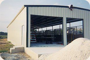 A white metal building with a large garage door is being built.