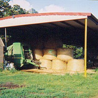 A shed filled with hay bales and a green machine.