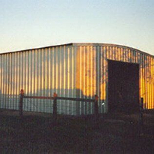 A large metal building with a wooden fence in front of it.