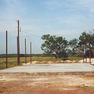 A concrete foundation is being built in a field with trees in the background.