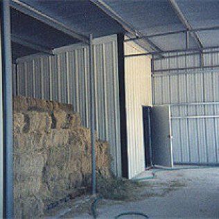 A barn filled with hay bales and a door.