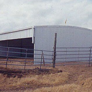 A large building with a fence around it is in the middle of a field.