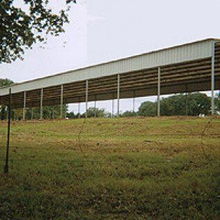 A large barn is sitting in the middle of a grassy field.