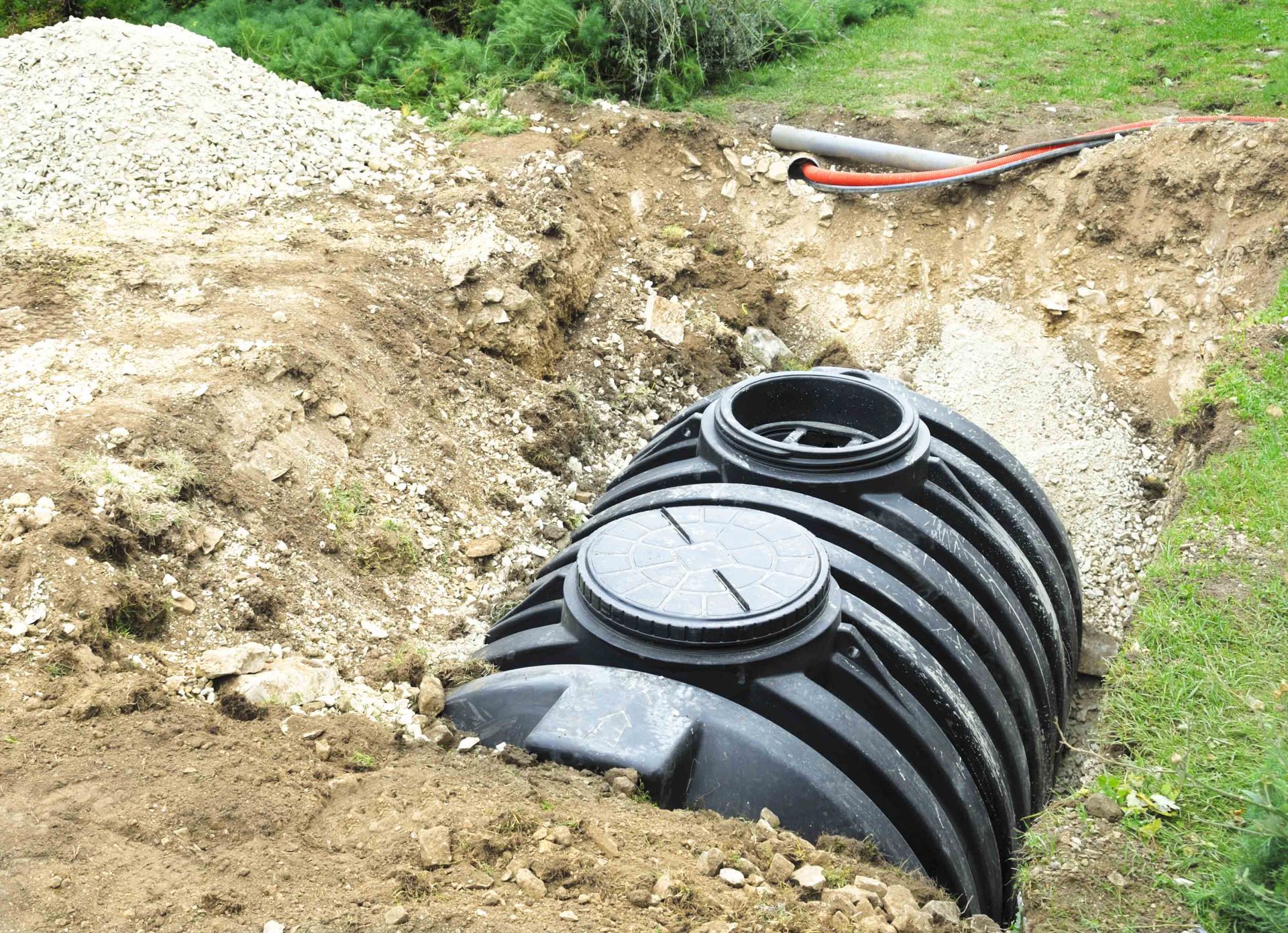 A Black Septic Tank Halfway Buried In Dirt Outside — Leicester, NC — Mike Septic Tank Services A Black Septic Tank Halfway Buried In Dirt Outside — Leicester, NC — Mike Septic Tank Services