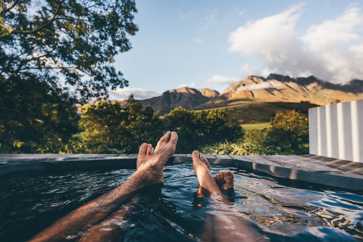 Two people are laying in a swimming pool with their feet in the water.