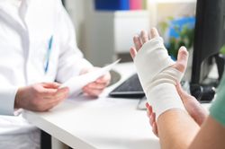 Bandaged hand held up during a doctor’s office consultation