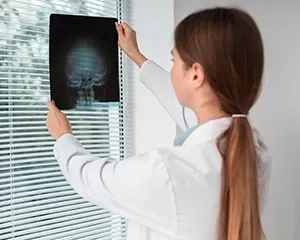 Person in white coat examining an X-ray film in a bright office