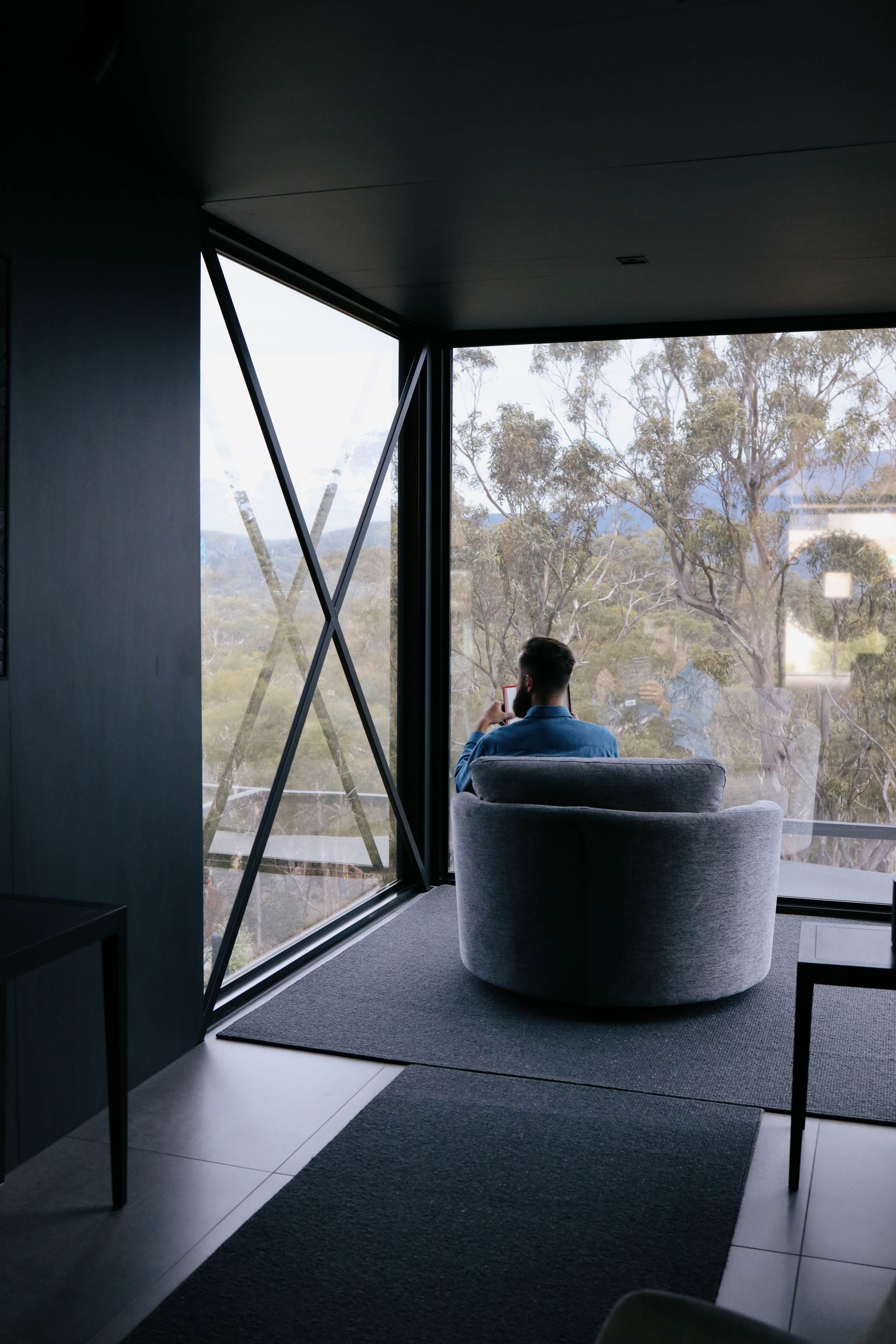 A man is sitting in a chair in front of a large window.