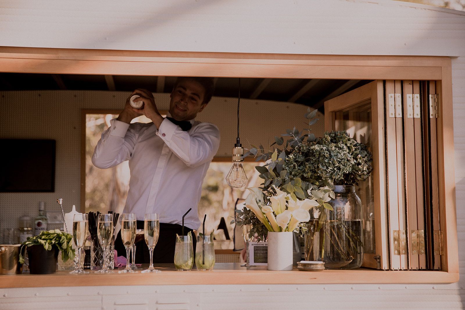 A man is standing behind a bar making a drink.