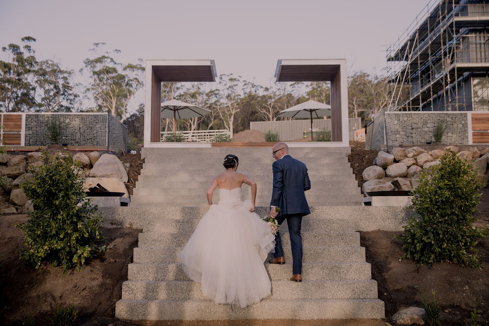 A bride and groom are walking down a set of stairs.