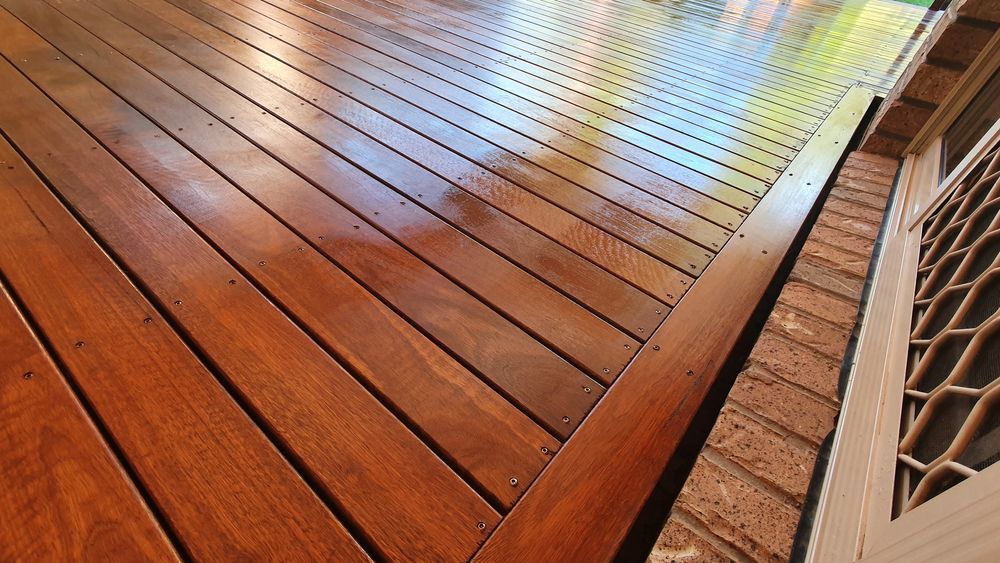 A Wooden Deck With a Brick Wall in the Background — Glen Lamberts Wall Cladding & Home Improvements in Maitland, NSW