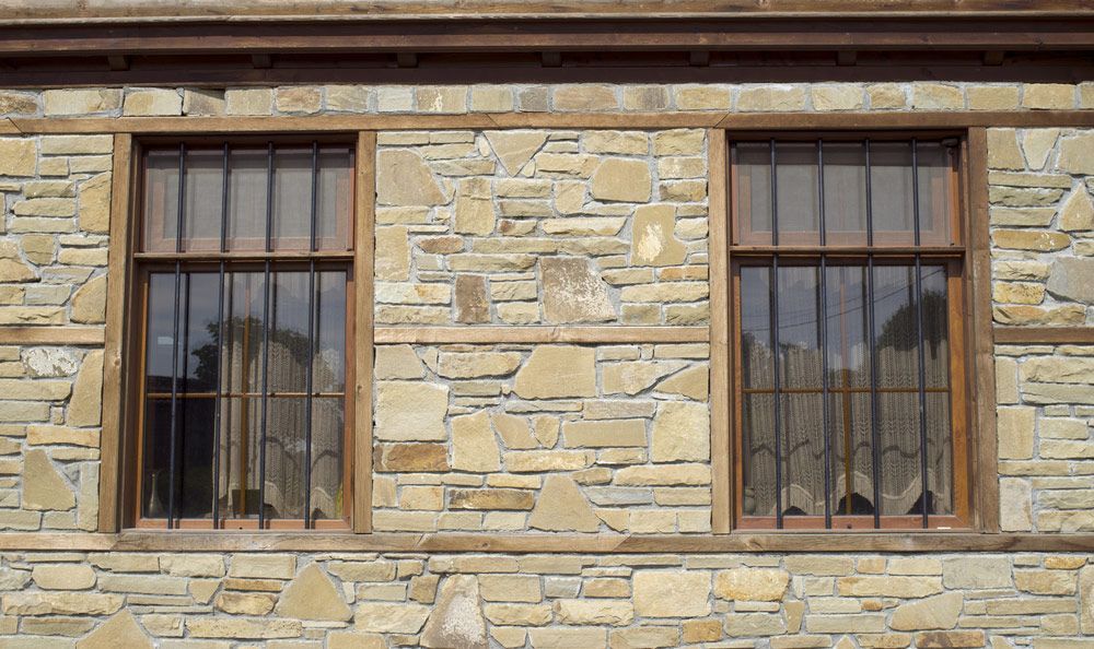A Stone Building With Two Windows and a Wooden Frame — Glen Lamberts Wall Cladding & Home Improvements in Gloucester, NSW