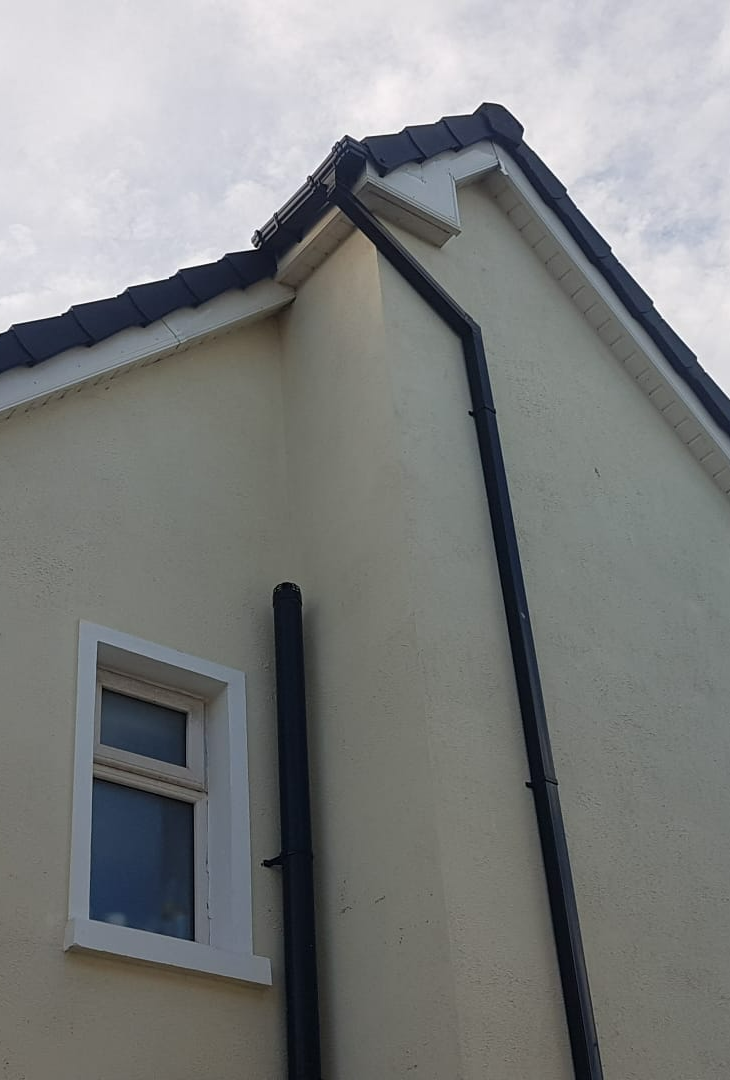 A white house with a black gutter and a window