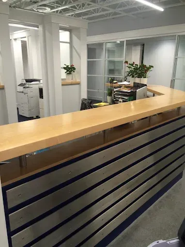 Shiny clean reception desk with wood counter, metal siding, and plants.