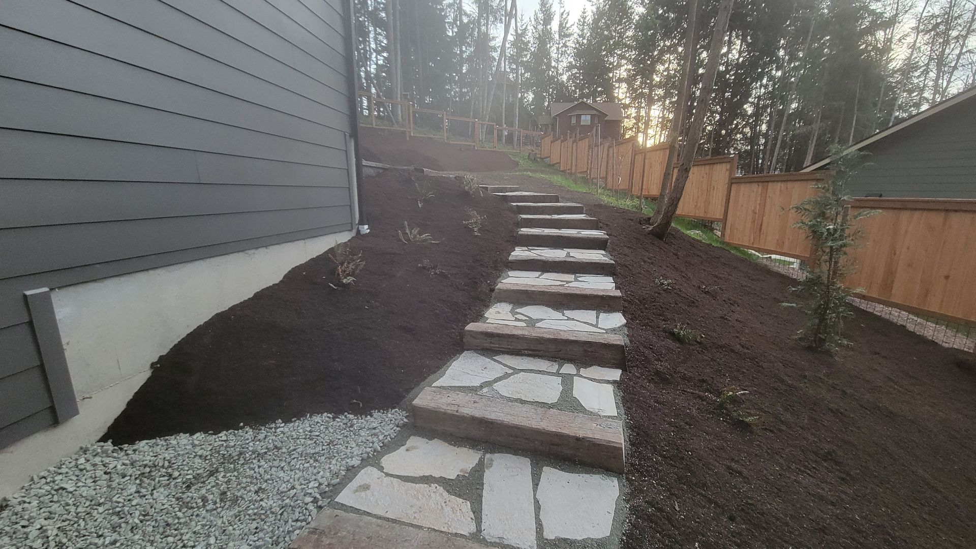 Bark mulch spilling from a white bag onto grass in a garden.