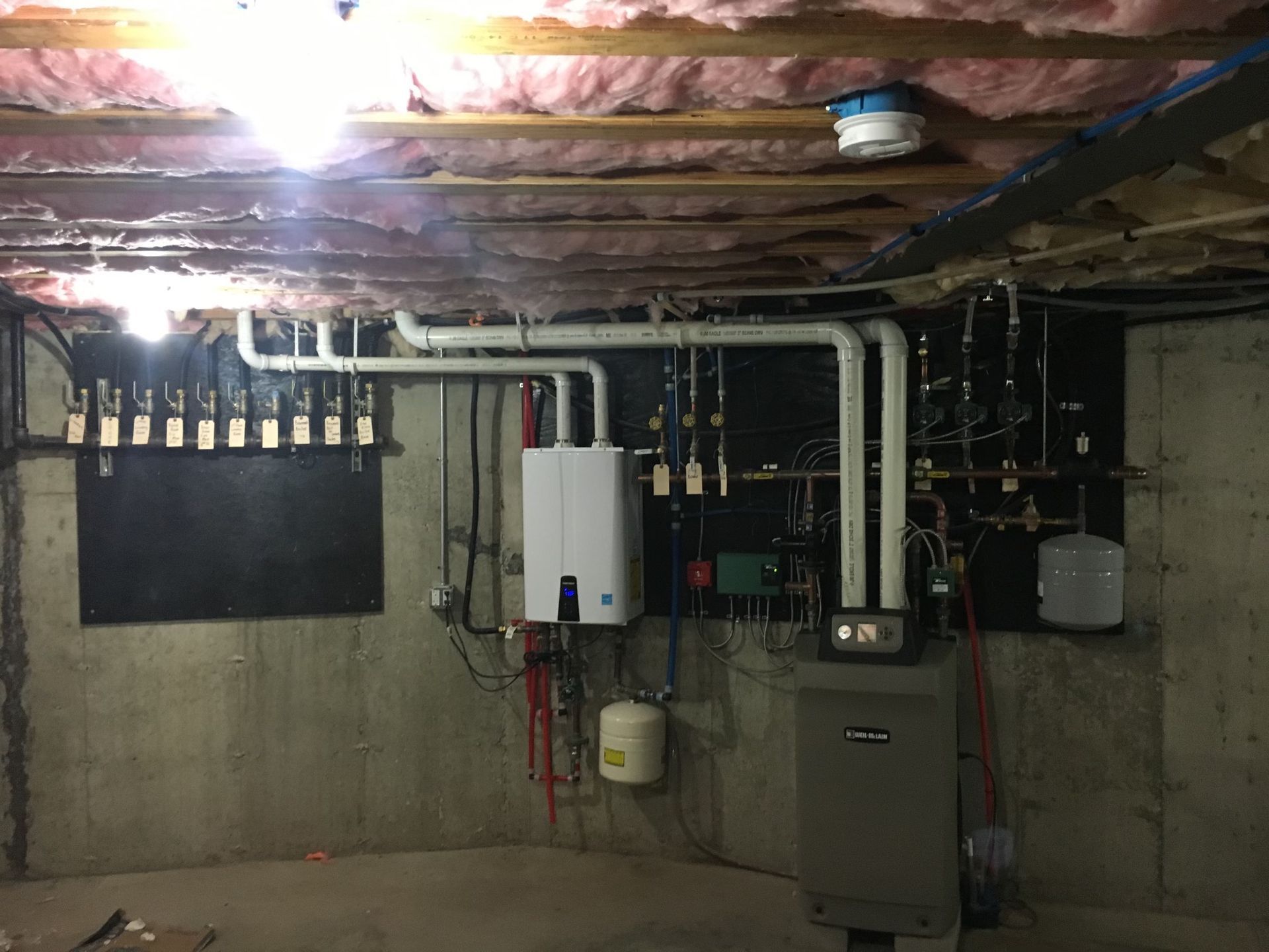 Worker in orange vest and blue overalls inspecting meters in an industrial setting.