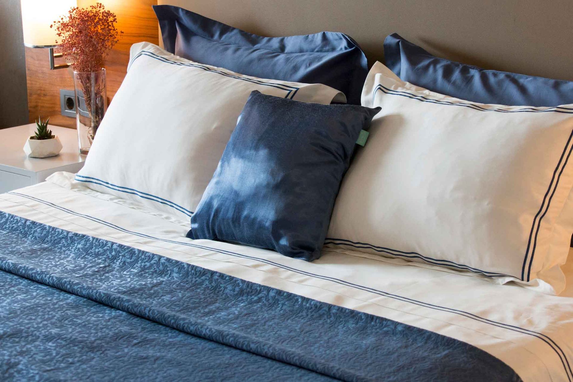 A bed with blue and white sheets and pillows in a bedroom.