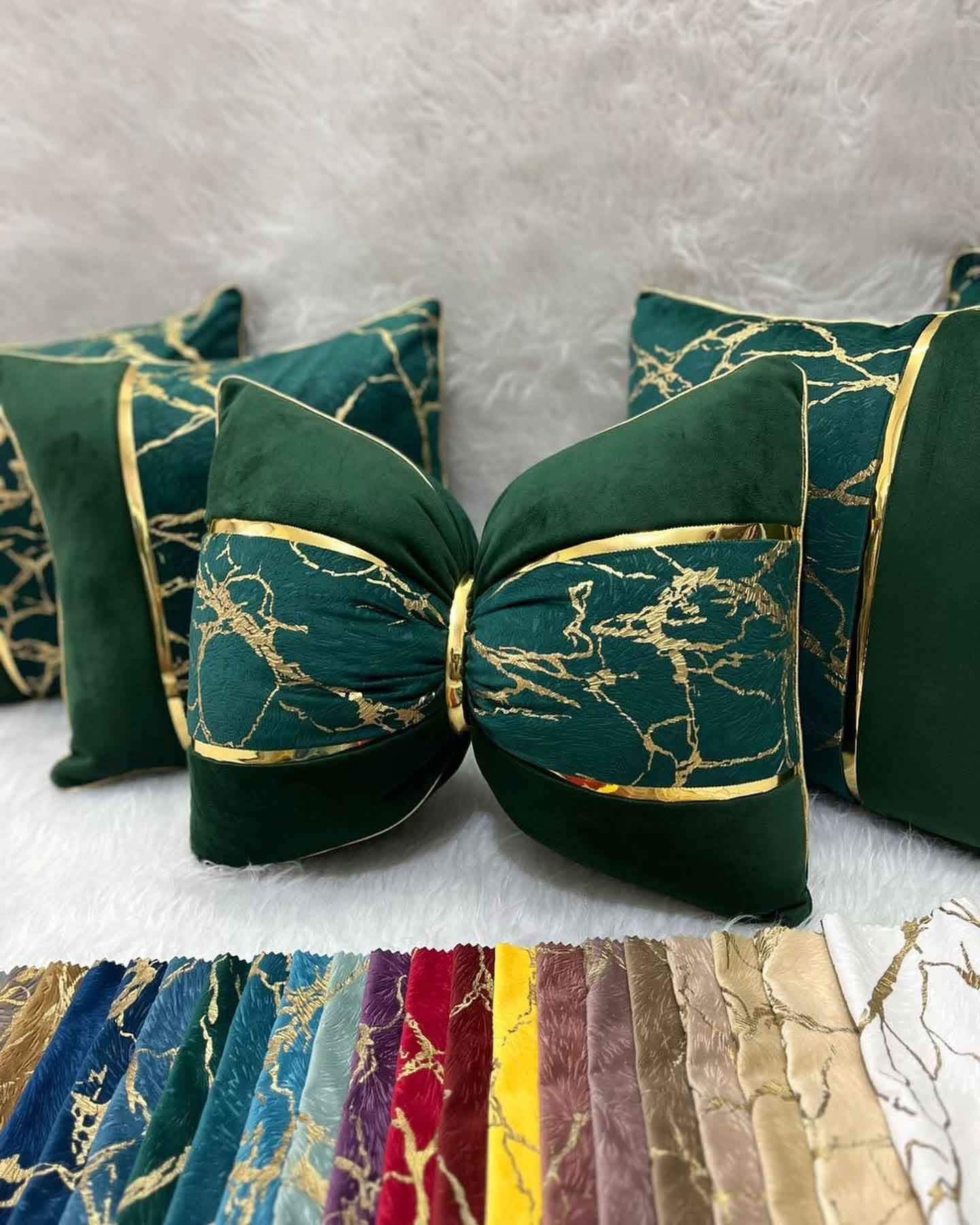 A green pillow with a bow on it is sitting on a table next to other pillows.