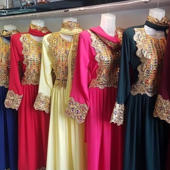 A row of dresses are lined up on mannequins in a store.