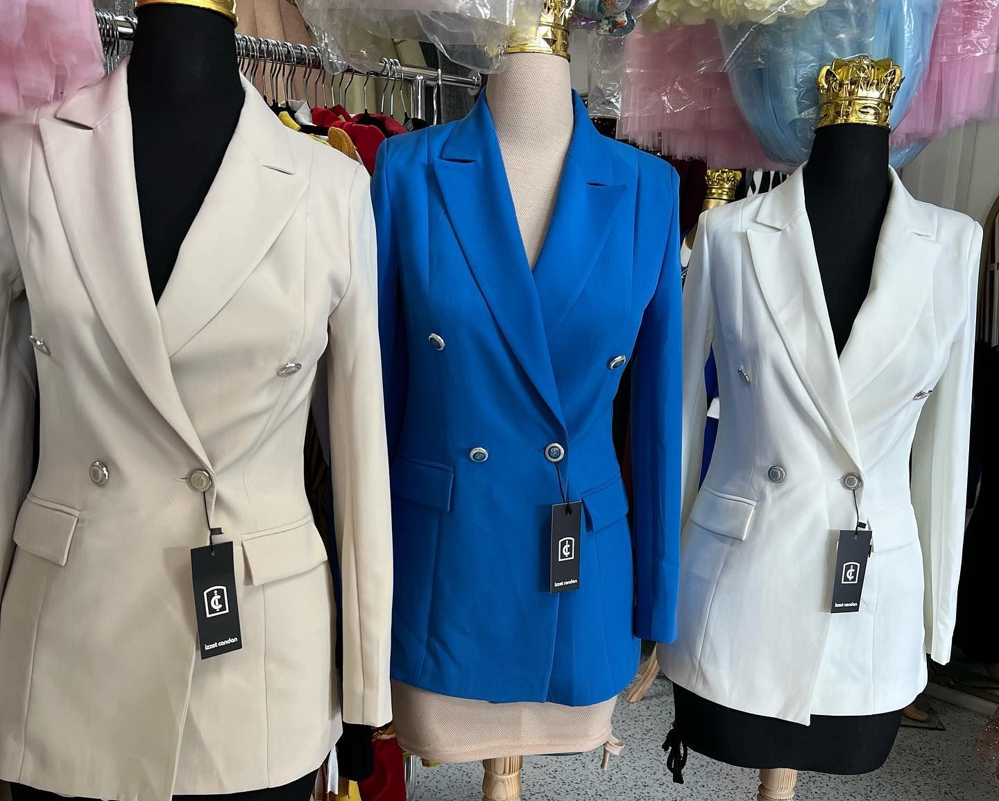 Three mannequins wearing different colored blazers in a store