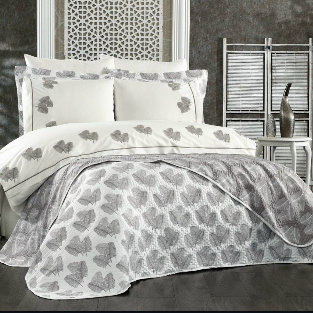 A bed with a grey comforter and white pillows