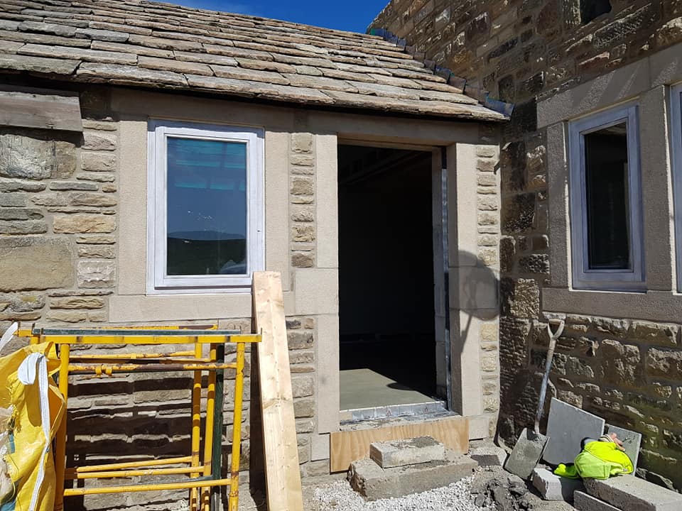 a stone building with a window and a door is being built .