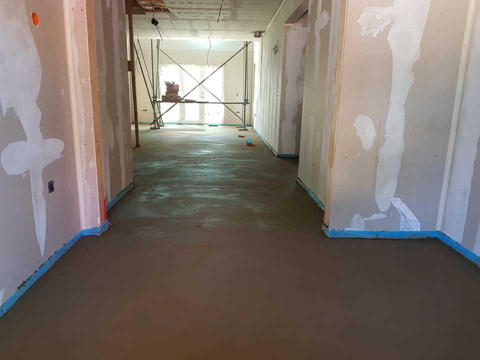 a hallway with a concrete floor in a building under construction .