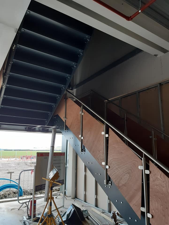 a staircase with a stainless steel railing is under construction in a building .