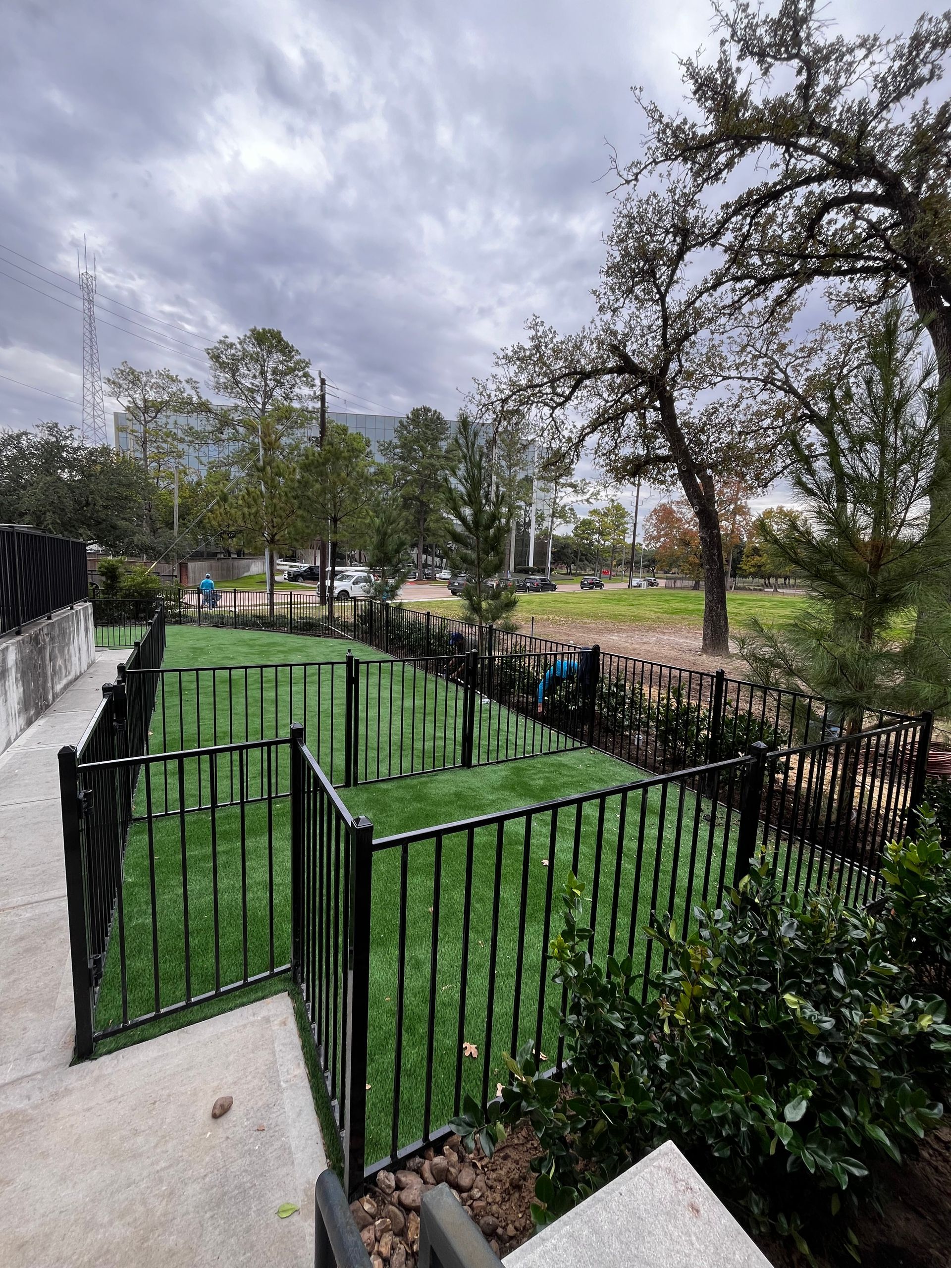 A fence surrounds a grassy field in a park.