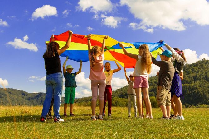 group of children playing under parachute outdoors