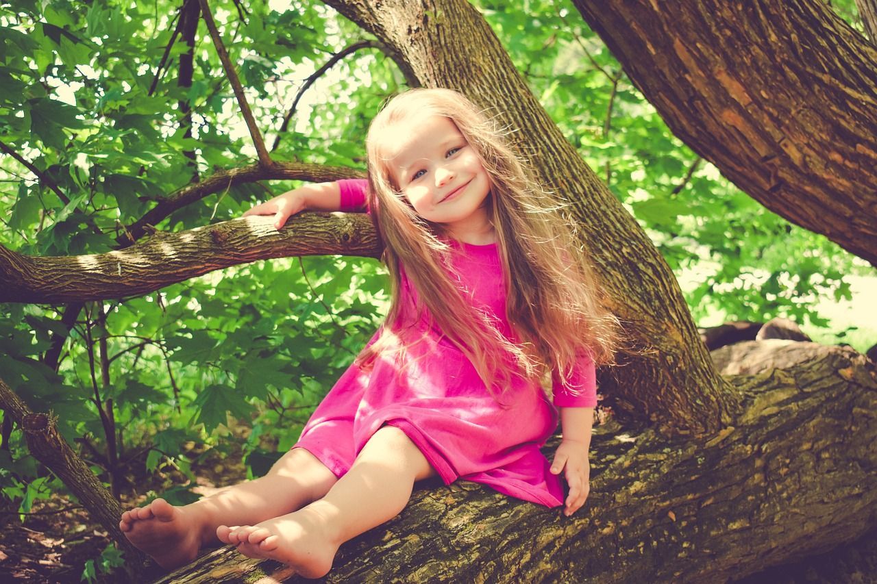 child climbing a tree barefoot