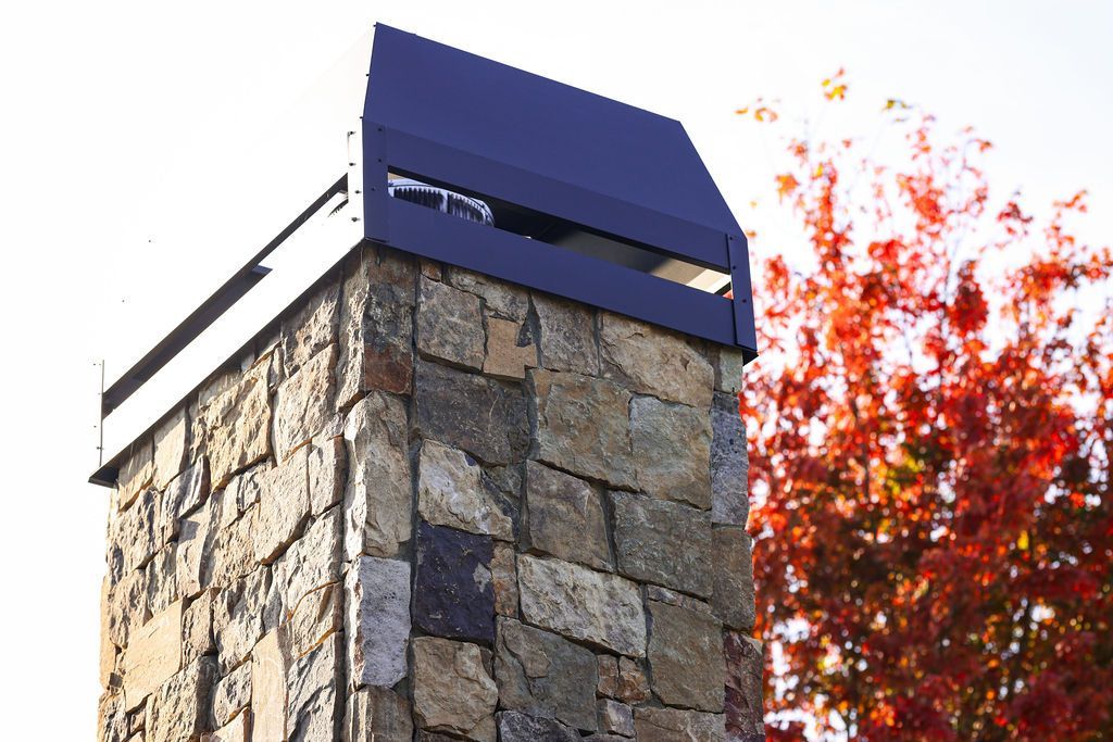 Outdoor stone fire place with cap and shroud