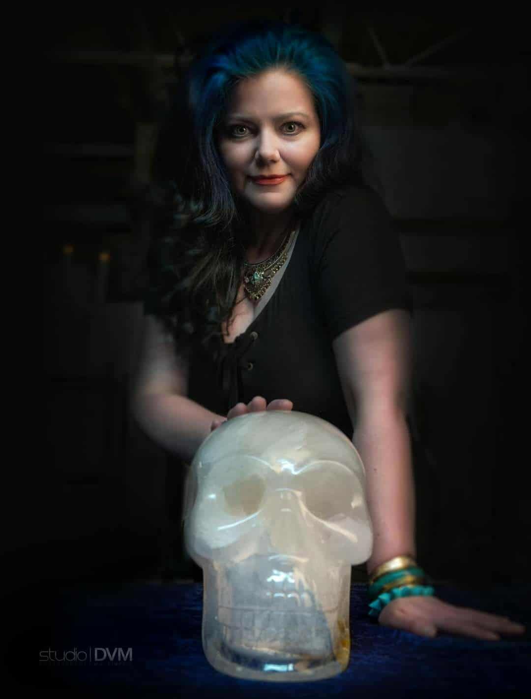 Woman holding jar of seeds, lit candle and seeds on table.