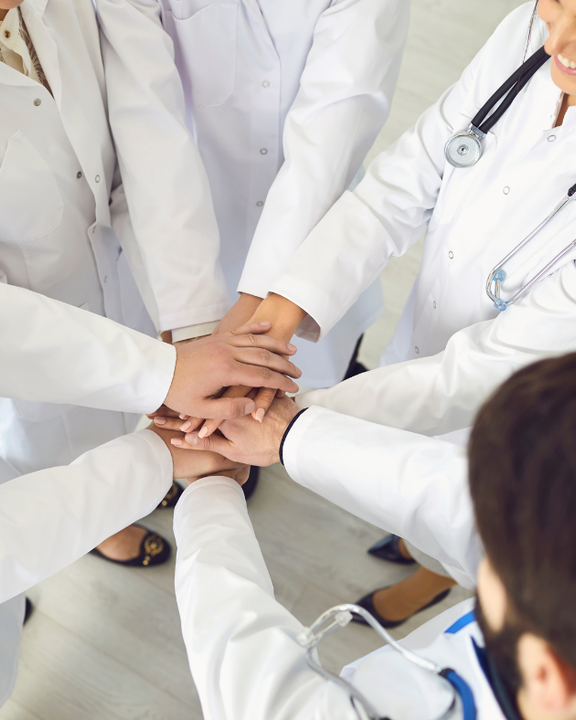 A group of doctors are putting their hands together