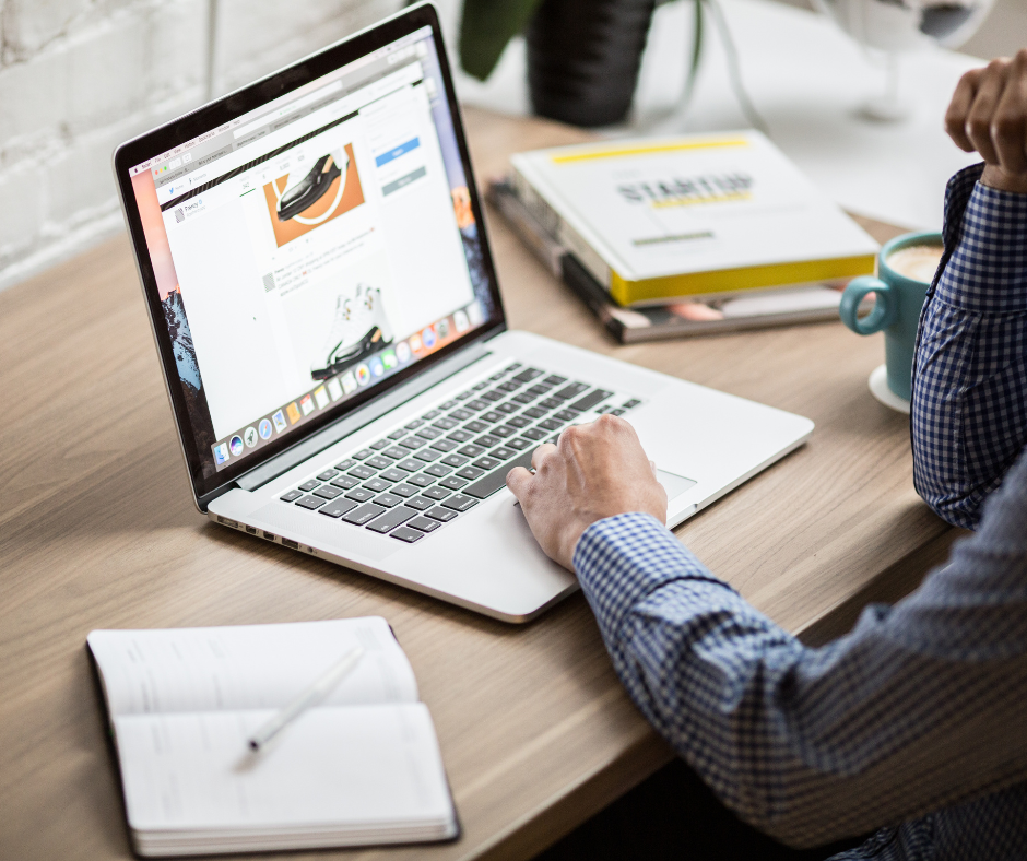 A man is typing on a laptop computer while sitting at a desk.