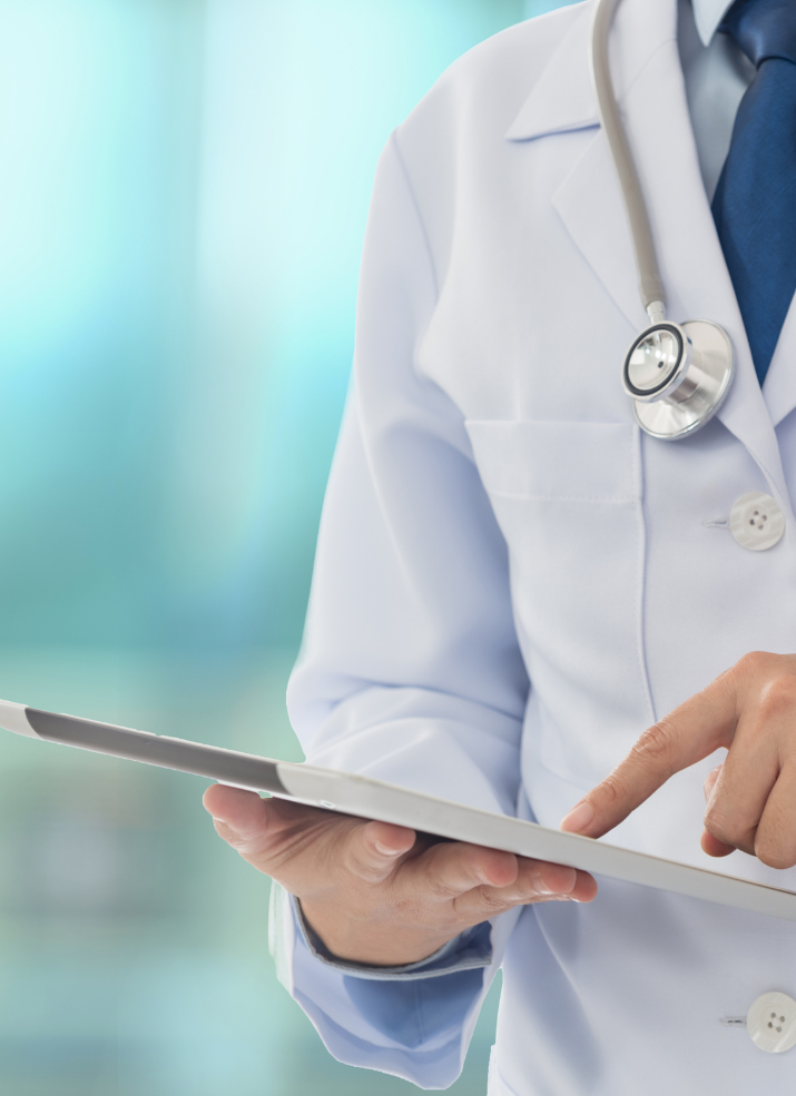 A doctor with a stethoscope around his neck is using a tablet