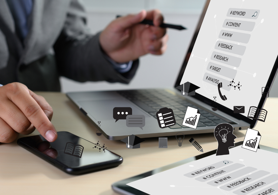 A man is using a laptop and a tablet while holding a pen.