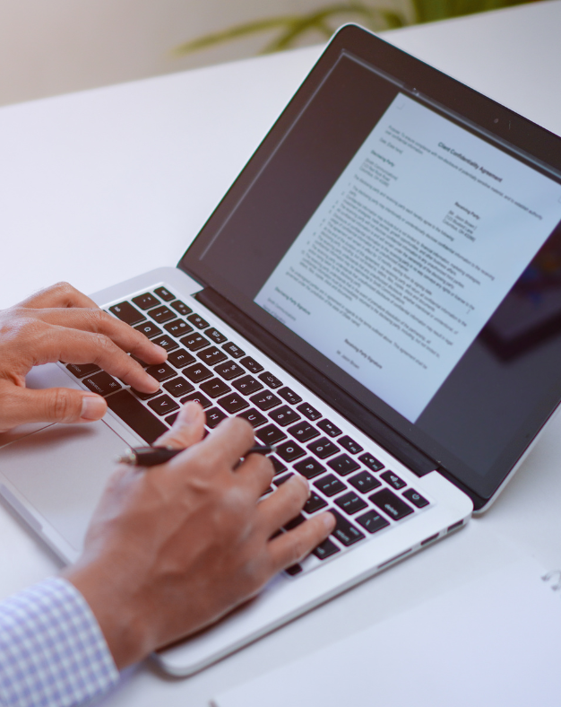 A person is typing on a laptop with a letter on the screen